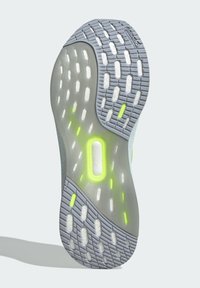 Apavu zolīte ar pelēku gumijas pamatni, fakturētu saķeres rakstu, caurspīdīgām daļām un spilgti zaļiem akcentiem, kas uzlabo redzamību.