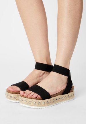 Black espadrille sandals with elastic straps, jute-wrapped sole, and decorative silver beads along the upper edge.  Ergonomically designed.