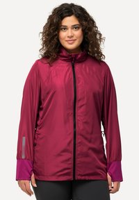 Burgundin kevytrakenteinen takki, jossa on korkea kaulus, vetoketjukiinnitys, joustavat hihansuut ja säädettävät sivuyksityiskohdat. Sisältää teksturoituja paneeleja hengittävyyden parantamiseksi.