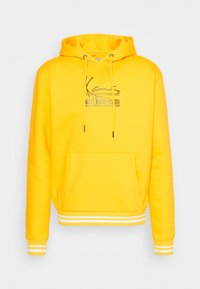 Sudadera amarilla de mezcla de algodón, con un bolsillo canguro en el frente, capucha con cordón y puños y dobladillo a rayas blancas. Logotipo en la parte frontal.
