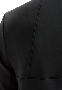 Zwarte sporttop van een gestructureerde stof met een ruitpatroon, ronde halslijn en contrasterende gladde panelen op de schouders.