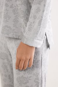 Lichtgrijze pyjama set met een bloemenpatroon. De mouw heeft een gladde satijnen manchetten, en de stof lijkt zacht en gestructureerd.