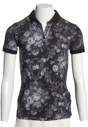 Sort kortærmet polo t-shirt med mørk krave og lysegråt blomster- og ornamentalmønster på en mannequin torso.