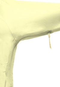 Makroaufnahme eines hellgelben Stoffjackenärmels mit sichtbarem Reißverschluss und gelbem Reißverschlusszug.