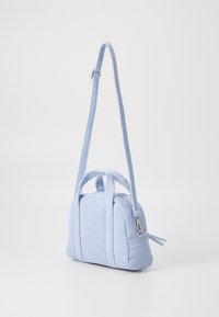 Sac en tissu bleu clair avec une texture nervurée, comportant une fermeture éclair, des poignées courtes et une bandoulière longue amovible.