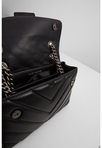 Borsa a tracolla in pelle nera con motivo a rombi trapuntati, tracolle in metallo argentato e chiusura a scatto. L'interno presenta diversi scomparti per un'organizzazione ottimale.