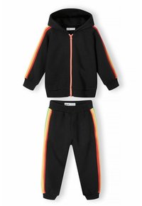 Svart huvtröja med dragkedja fram, accentuerad med röda, orange och gula ränder på ärmarna; matchande svarta byxor med färgade sidostripes.