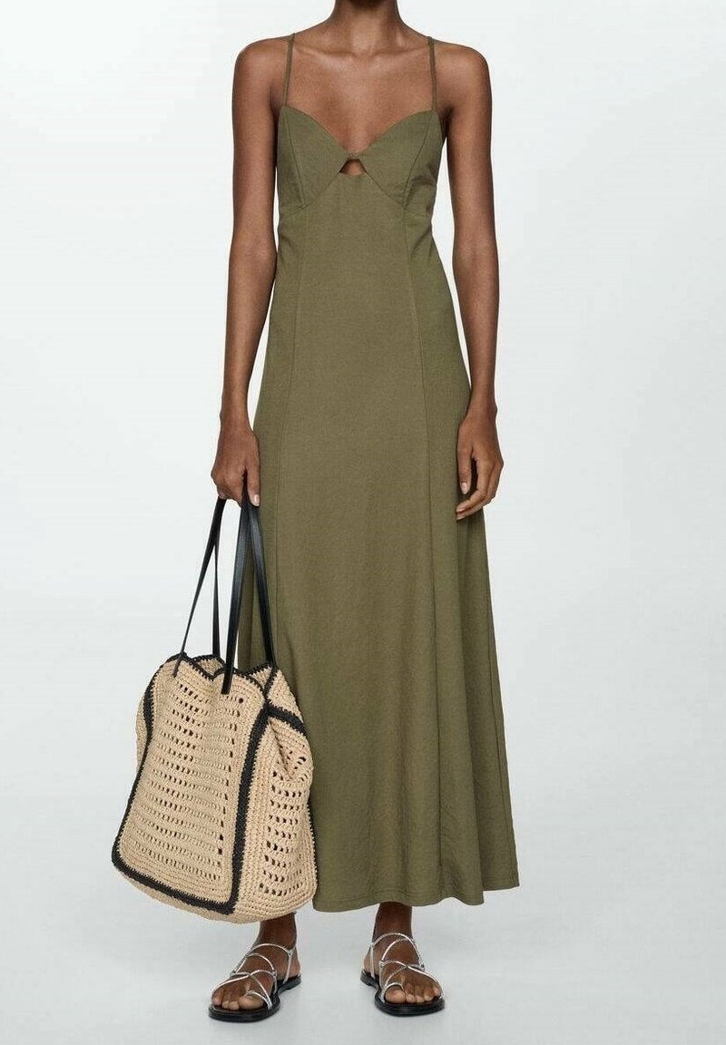 Robe maxi sans manches vert olive avec un détail en forme de goutte et un corsage ajusté. Associée à un sac fourre-tout beige tissé à motif et des sandales plates.