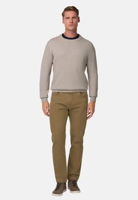 Suéter texturizado gris claro, pantalones khaki de corte slim y zapatillas gris oscuro. Diseño simple con ribetes acanalados y silueta ajustada.