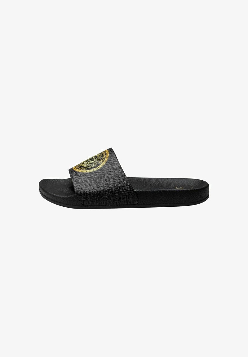 Black slide sandal with a textured upper and a wide strap featuring a circular gold graphic. Flat sole for casual wear.