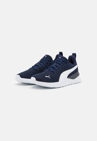 Baskets de sport bleu marine en tissu mesh, avec des accents blancs, un design à lacets, des semelles rembourrées et une languette au talon pour un enfilage facile.