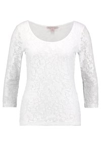 Vit långärmad topp med ett blommönstrat spetsmönster, rundad halsringning och figurnära passform. Mjuk textur med intrikata detaljer genom hela plagget.