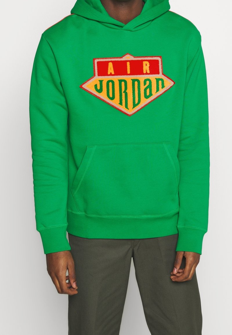 Sudadera verde con un gran logo "AIR JORDAN" en rojo, amarillo y naranja. Presenta un bolsillo frontal y puños y dobladillo acanalados. Fabricada en tela suave.