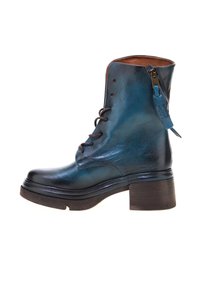 Kožne gležnjače u tamno plavoj boji s sjajnom završnom obradom, okrugli vrh, vezanje sprijeda i bočni patentni zatvarač. Debela drvena peta za dodatnu visinu.