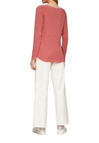 Langmouwige, rozenkleurige top met een ronde hals, gecombineerd met witte wijde broek en lichtgekleurde sneakers. Gladde textuur, casual pasvorm.