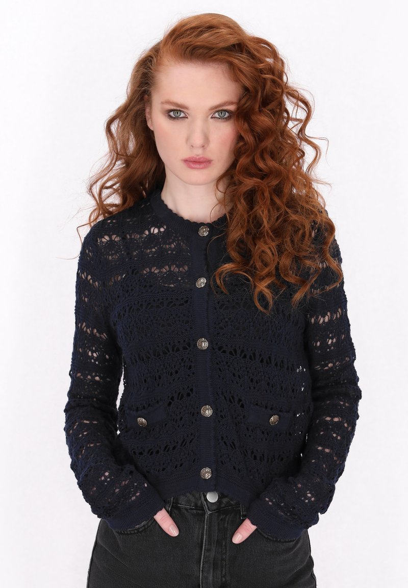 Marineblauer Strickcardigan mit filigranem Spitzenmuster, langen Ärmeln, vorderen Taschen und metallischen Knöpfen. Sanfter Stoff.