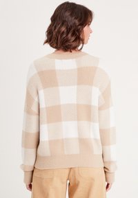Beige und weiße karierte Sweater aus weichem Stoff. Bietet eine lockere Passform und gerippte Bündchen, mit einem runden Halsausschnitt und überschnittenen Schultern.