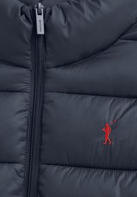 Marinblå vadderad jacka med dragkedja och dragkedjehänge märkt "Polo Club" samt liten röd broderad polo-spelare på bröstet.