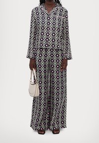 Ensemble de pyjama à manches longues à motifs floraux en noir, blanc et rose. Comprend une chemise à boutons et un pantalon large. Tissu lisse avec un motif répétitif.