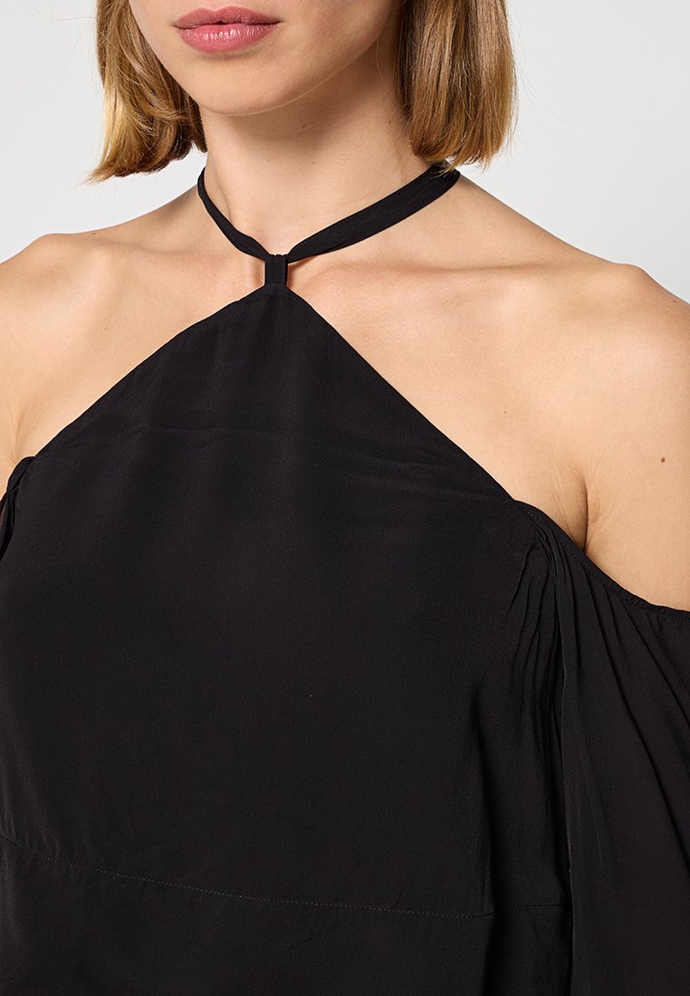 Top nero a trapezio con un design triangolare, caratterizzato da una sottile tracolla, una texture morbida e dettagli di tessuto arricciato lungo le spalle.