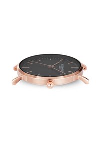 Reloj redondo con un dial negro, caja de acero inoxidable en oro rosa, marcadores de hora minimalistas y una corona con agarre texturizado.