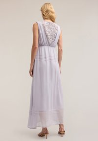 Lila Maxikleid mit Spitzenrücken und gefältelten Akzenten an der Taille. Weicher, transparenter Stoff fällt elegant bis zum Boden.