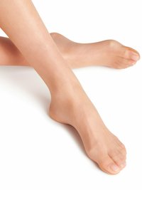 Collant trasparenti nudi con piedi su gambe incrociate, caratterizzati da una consistenza liscia e un tono uniforme, con un aspetto naturale della pelle e unghie dei piedi curate.