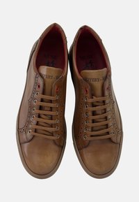 Zapatillas de cuero marrón con un diseño de bajo perfil, punta redonda, forro interior rojo, costuras decorativas y cordones planos con ojales de metal.