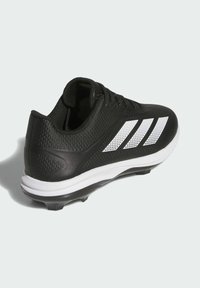 Crna atletska cipela s teksturiranim gornjim dijelom, s bijelim prugastim naglascima, vezanjem na vezice i izdržljivim gumiranim potplatom sa studovima.