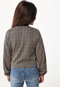 Karo svetr v béžových, námořnických a růžových tónech; má kulatý výstřih a dlouhé rukávy. V kombinaci s modrými upnutými džíny.