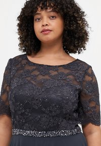 Rochie bleumarin din dantelă, cu mâneci scurte, model floral și embellismente cu mărgele la talie. Țesătură netedă sub stratul de dantelă.