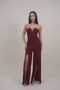 Burgundy strapless jumpsuit with a deep V-neck, featuring high side slits, fitted bodice, and wide leg design. Smooth fabric texture.