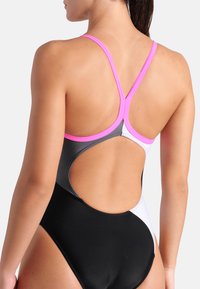 Il costume da bagno intero presenta un design color block con pannelli rosa, neri e bianchi; spalline incrociate sottili; e una schiena scoperta.