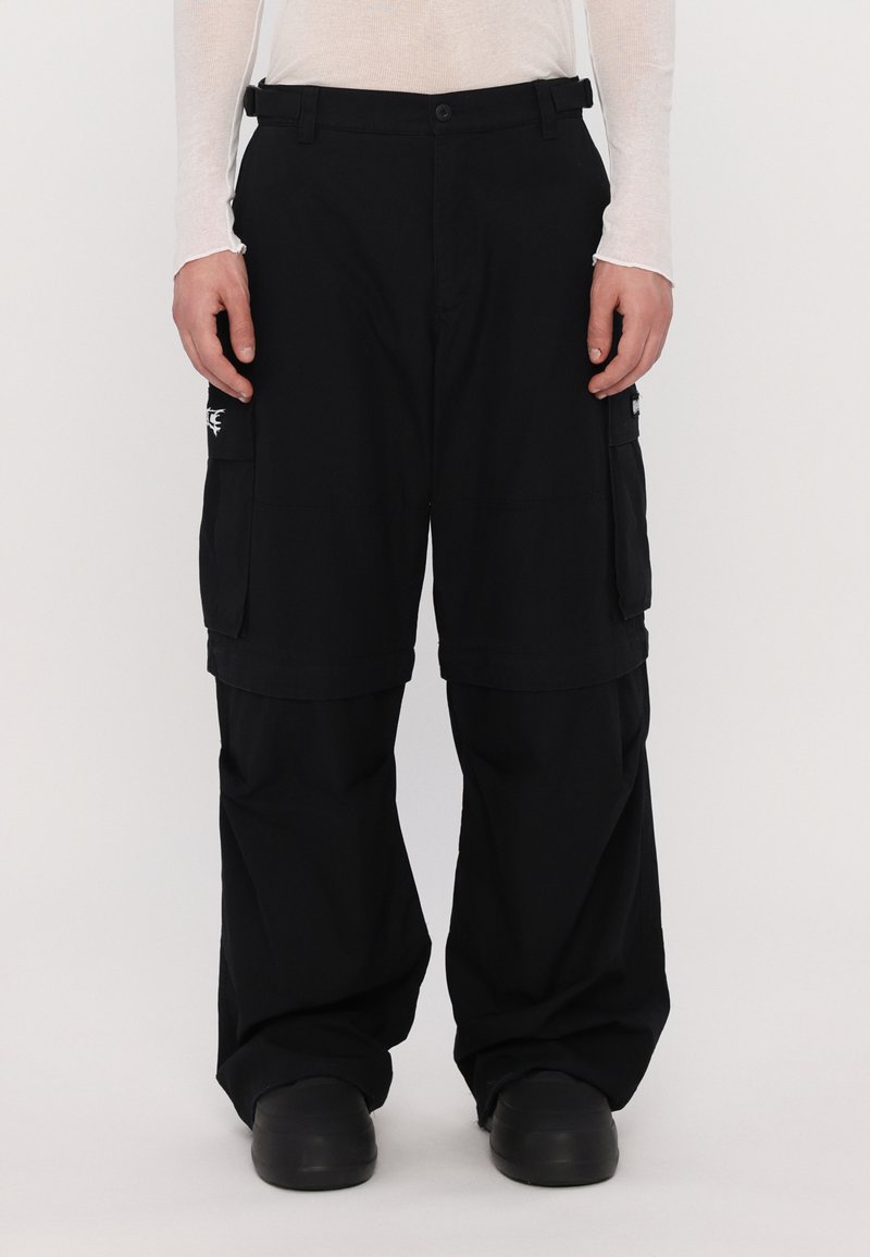 Pantalones cargo negros fabricados con un tejido duradero, con un ajuste holgado, múltiples bolsillos y un distintivo logo sutil en el lateral.