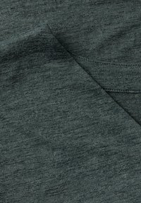 Tessuto texturizzato di un verde scuro con un motivo a maglia morbido. Il materiale sembra elastico e leggero, mettendo in mostra varie tonalità all'interno della trama.
