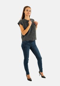 Top grigio in maglia a maniche corte con una vestibilità rilassata, abbinato a jeans skinny blu scuro e scarpe con tacco nero a punta.