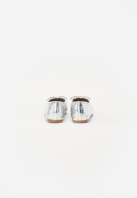 Sömlösa silvermetalliska ballerinaskor med rund tå och en liten slinga på hälen, med en ljusfärgad sula.