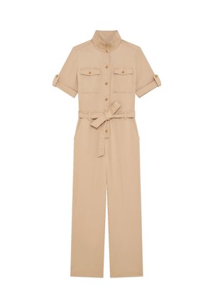 Beżowy kombinezon roboczy z krótkimi podwiniętymi rękawami, zapinany z przodu na guziki, z klapami na kieszeniach na piersi i paskiem wiązanym w talii.
