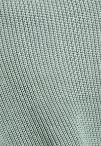 Tissu tricoté de couleur vert clair douce avec une texture côtelée, présentant des lignes horizontales uniformément espacées et de légères variations de ton.