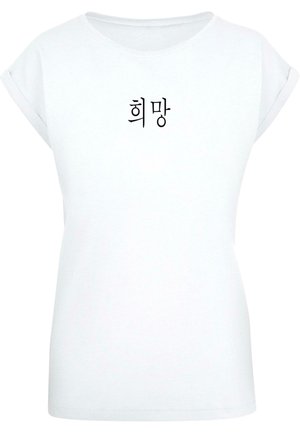 Valkoinen puuvillapaita, jossa on käännetyt hihat, ja johon on painettu mustalla koreankielisellä tekstillä "희망" (toivo) keskitetysti etuosaan.