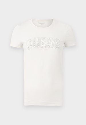 Fehér rövid ujjú, kerek nyakú póló, amelyen a mell részen "GUESS" logó apró strasszkövekkel díszítve.