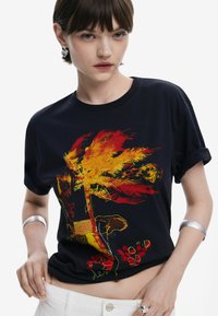 Schwarzes Baumwoll-T-Shirt mit lebhaftem roten und gelben grafischen Design eines Palmenbaums und abstrakten Mustern, mit hochgekrempelten Ärmeln und lockerer Passform.