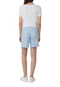 Shorts bleu clair avec un ourlet retroussé, une taille élastique et deux poches arrière. Associés à une chemise blanche à manches courtes et des baskets blanches.