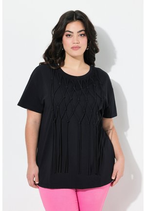 Sort t-shirt med et struktureret design af sammenflettede stofstrenge, korte ærmer og rund halsudskæring, parret med pink bukser.
