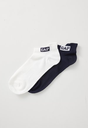 Chaussettes en coton à chevilles, l'une blanche et l'autre marine, avec une texture côtelée et une étiquette de logo sur les bords.