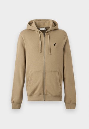 Μπεζ φούτερ με φερμουάρ, εμπρός τσέπες, κουκούλα με κορδόνια, ριμπ μανσέτες και μικρό μαύρο λογότυπο πουλιού στο αριστερό στήθος.