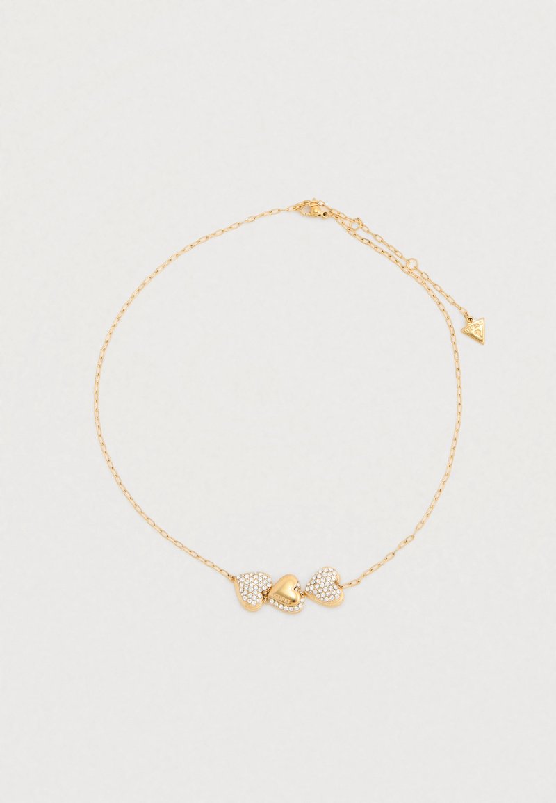 Βραχιόλι σε χρυσό τόνο με τρεις καρδιές: κεντρική γυαλιστερή καρδιά και δύο καρδιές με στρας στα πλάγια, με λεπτή αλυσίδα και ρυθμιζόμενο κούμπωμα.