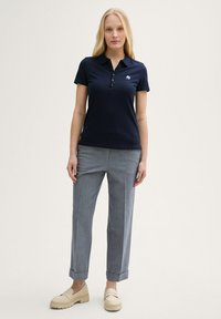 Mornarji polo majica s kratkimi rokavi in zapenjanjem. Sive elegantne hlače z majhno manšeto. Bež loafers čevlji. Preprost logotip na majici.