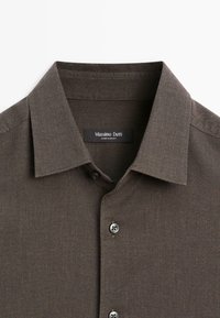 Braunes, strukturiertes Hemd mit Knopfleiste, klassischem Kragen, schwarzem Markenlabel und grauen Knöpfen. Hergestellt aus weichem Material.