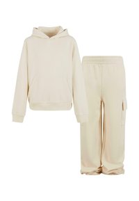 Ljusbeige huvtröja med en framficka, tillsammans med matchande sweatpants med en sidoficka, båda i mjukt tyg.